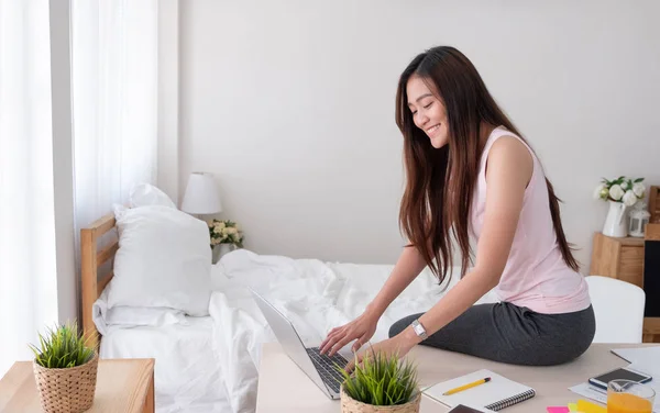 Asiatico femmina freelancer sedersi su tavolo lavoro a laptop in bedroo — Foto Stock