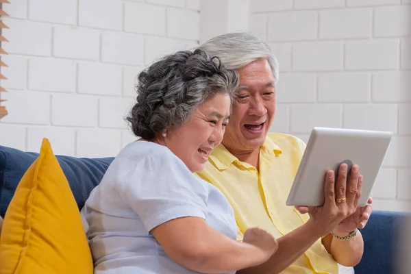 Asyalı yaşlı çift tablet görüntülü arama ve torun konuşmak kullanın — Stok fotoğraf