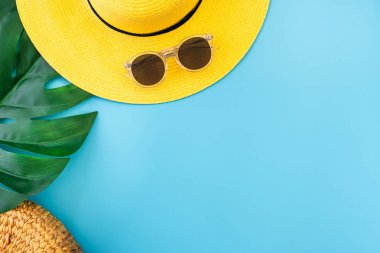 sarı şapkalı yaz mavisi afiş, güneş gözlüğü ve monstera yaprağı