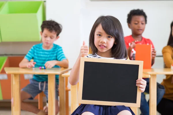 Kid flicka håller tom blackboard med mångfald vänner och te — Stockfoto
