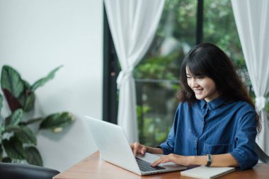 Asyalı kadın café restaur pencerede yakınındaki dizüstü bilgisayarda kullanma