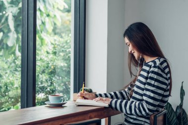 Asyalı kadın mobil oturan müzik dinleme kitap yazma 