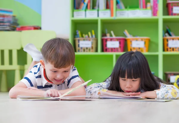 Dos niños se tumbaron en el suelo y la lectura de libros de cuentos en preescolar lib —  Fotos de Stock