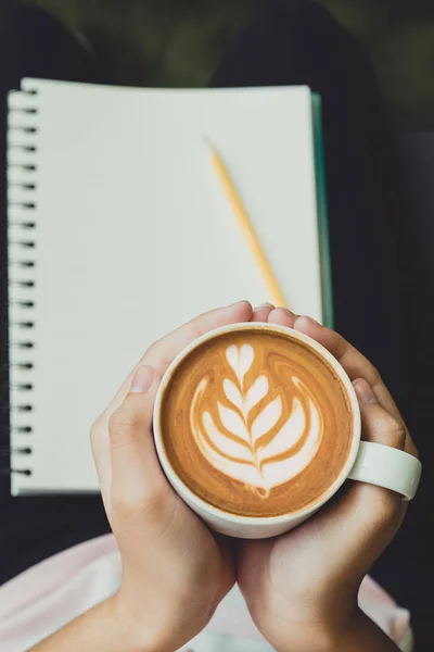 Z bliska ręka trzyma filiżankę gorącej cappuccino z sercem latte — Zdjęcie stockowe