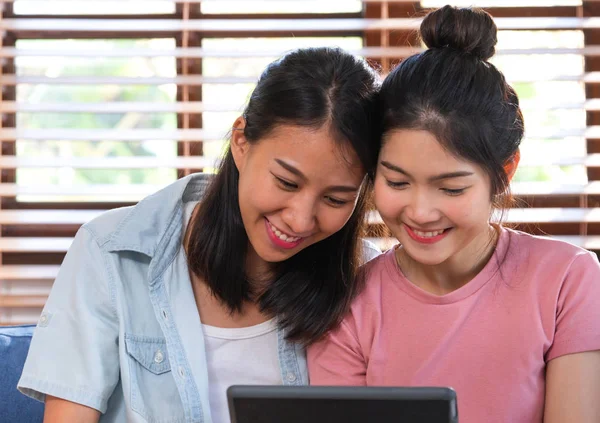 Щасливі азіатські лесбіянки дивитися відео на планшеті на дивані в будинку.LG — стокове фото