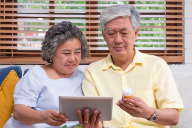Asian senior couple use tablet computer searching about doctor p