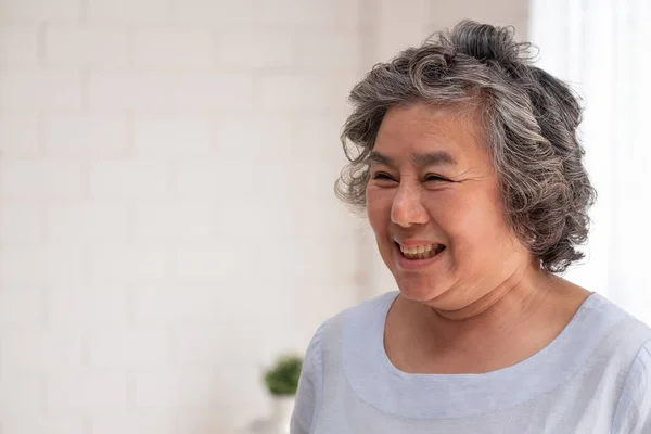 Asiatische Seniorin lächelt im Wohnzimmer zu Hause, glückliches Altern bei h — Stockfoto