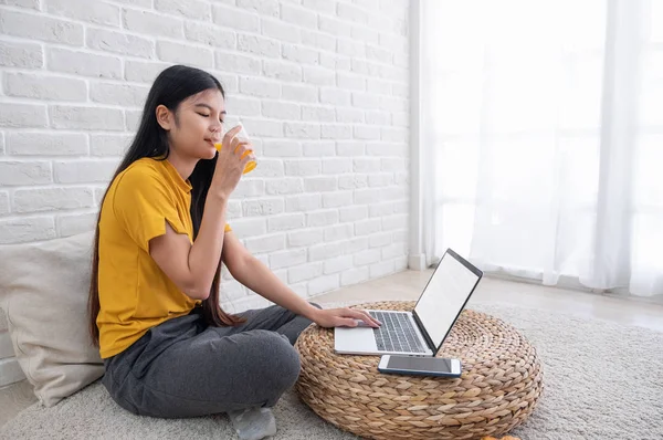 Asiatico femmina sedersi su pavimento utilizzando laptop su vimini stand e bere — Foto Stock