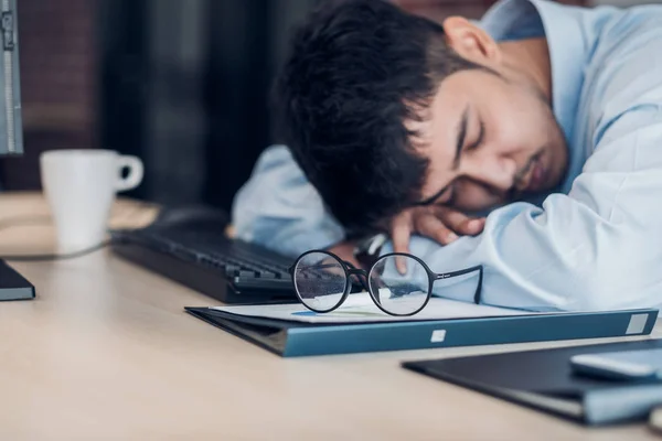 Tired asian businessman sleep on working desk table in office.wo