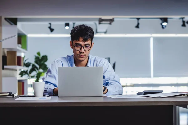 Asiatischer Geschäftsmann wacht mit Laptop und Papierkram am Schreibtisch auf — Stockfoto