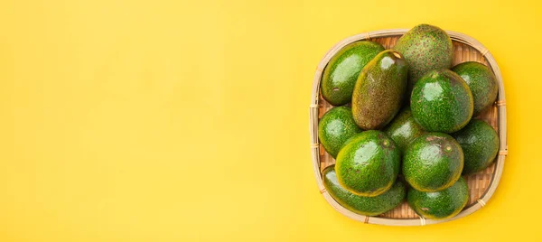 Sarı masa backgroun üzerinde sepet içinde organik avokado bütün meyve — Stok fotoğraf