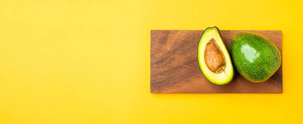 Aguacates ecológicos medio cortados con semilla y fruta entera en madera tr —  Fotos de Stock