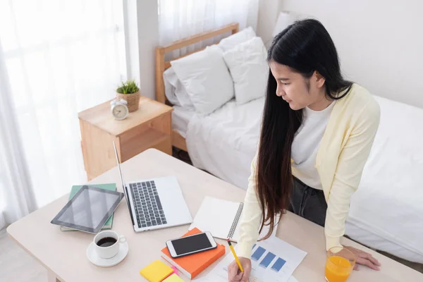 Asiatico femmina freelancer lettura relazione su laptop su tavolo in letto — Foto Stock