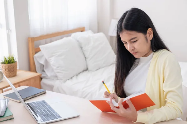 亚洲女性自由职业者阅读和记下笔记的书，而 — 图库照片