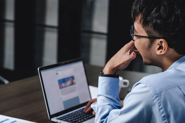 Asiatischer Geschäftsmann wacht mit Laptop und Papierkram am Schreibtisch auf — Stockfoto