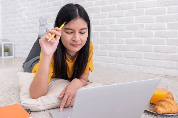 Donna asiatica sdraiata su tappeto e scrittura su notebook e apprendimento — Foto Stock