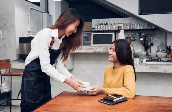 Jovem mulher asiática barista segurar xícara de café servindo um cliente em th — Fotografia de Stock