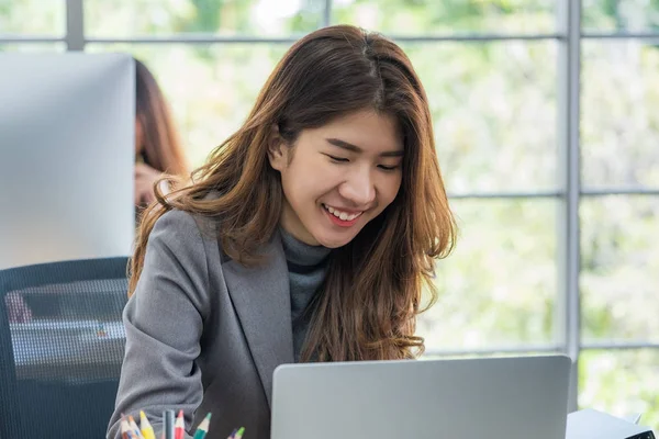 Feliz asiático mujer de negocios trabajando en portátil en oficina —  Fotos de Stock