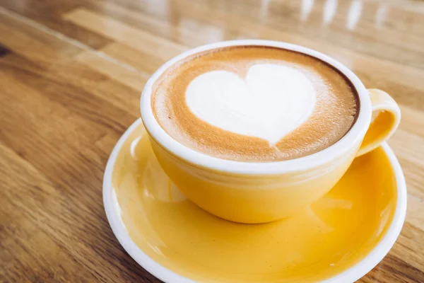 Tazza di caffè caldo cappuccino su vassoio di legno con arte del latte del cuore su — Foto Stock