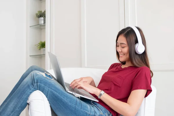 Mulher asiática ouvindo música no fone de ouvido e usando laptop comput — Fotografia de Stock