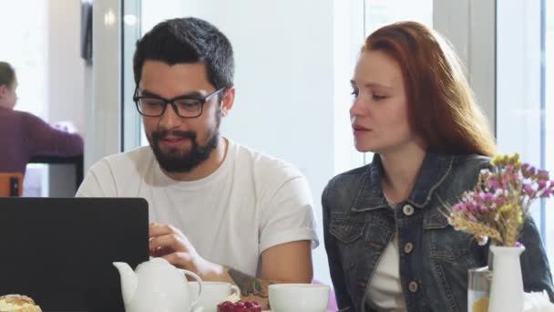 Casal encantador usando gadgets juntos enquanto toma café da manhã no café — Vídeo de Stock