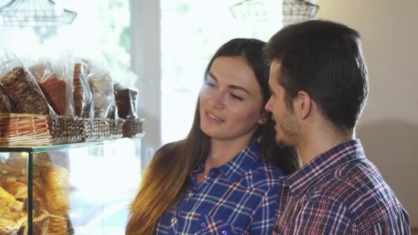 Close up tiro de um casal encantador escolhendo sobremesas na loja de padaria — Vídeo de Stock