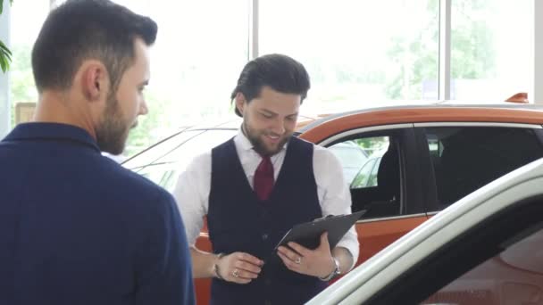 Bello maschio rivenditore di auto parlando con il suo cliente maschile — Video Stock