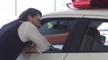 Yeni bir otomatik incelenirken kameraya gülümseyen yakışıklı adam