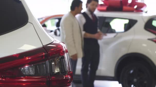 Επαγγελματικό αυτοκίνητο πωλητής δείχνοντας τα αυτοκίνητα για την πώληση σε πελάτη του αρσενικό — Αρχείο Βίντεο