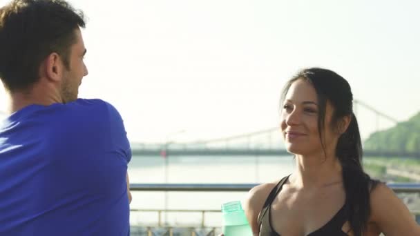 Hermosa mujer joven hablando con su amigo varón mientras hacen ejercicio juntos — Vídeo de stock