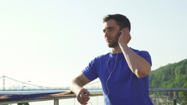 Happy handsome man enjoying listening to music outdoors after working out — Stock Video