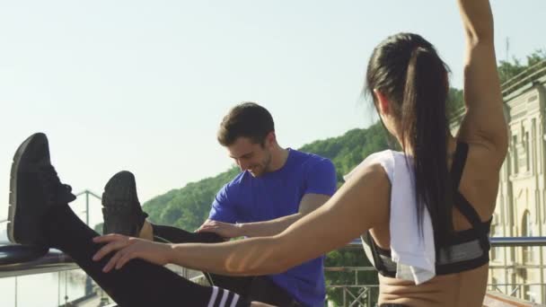 Jeune couple athlétique s'étirant ensemble à l'extérieur avant la course du matin — Video
