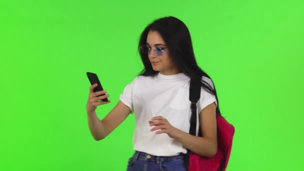 Charming female student with a backpack taking selfies with her smart phone — Stock Video