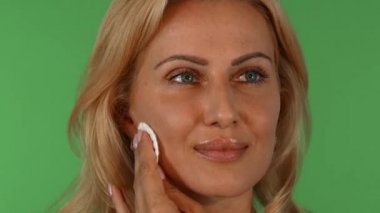 Yüzünü bir pamuk pad ile silerek çarpıcı bir olgun kadın portresi