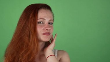 Yeşil arka plan üzerinde poz uzun kızıl saçlı güzel kadın