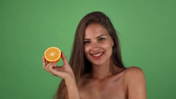 Studio shot van een prachtige gelukkige vrouw die lacht bezit de helft van een sinaasappel — Stockvideo