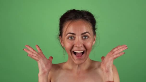 Jonge mooie vrouw op zoek naar enthousiast poseren op groene achtergrond — Stockvideo