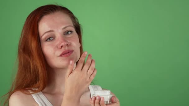 Attraente giovane donna dai capelli rossi che applica la crema viso — Video Stock