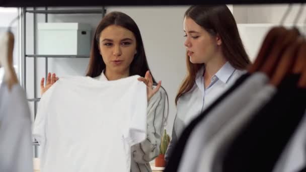 Dos trabajadoras de la tienda de moda discutiendo ropa en la pantalla — Vídeo de stock