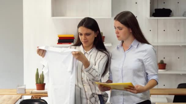 Diseñadora de moda y su colega discutiendo la línea de ropa en la oficina — Vídeos de Stock