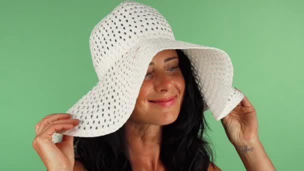 Attraktiv kvinna ler till kameran iklädd vit hatt — Stockvideo