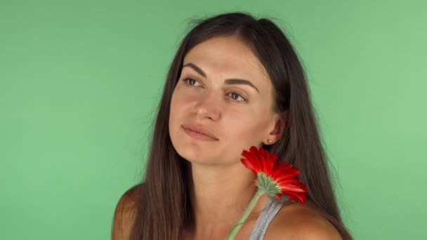 Чудова жінка посміхається, дивлячись мрійливо тримаючи квітку — стокове відео