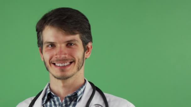 Alegre médico masculino sonriendo sosteniendo la píldora azul sobre fondo verde — Vídeos de Stock