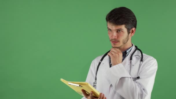 Bonito médico masculino ter uma ideia enquanto examina documentos — Vídeo de Stock