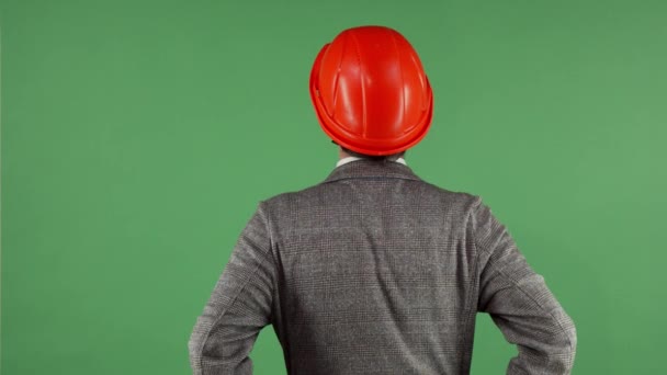 Vista trasera de un contactor con casco mirando alrededor en chromakey — Vídeos de Stock