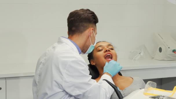 Dentista masculino alegre sorrindo enquanto examina os dentes de uma paciente do sexo feminino — Vídeo de Stock