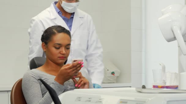 Joven mujer alegre y su dentista sonriendo a la cámara — Vídeos de Stock