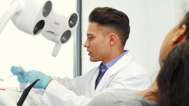 Profissional dentista masculino examinando os dentes de seu paciente — Vídeo de Stock