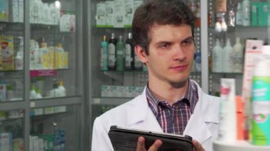 Yakışıklı profesyonel eczacı dijital tablet kullanarak stok yapıyor