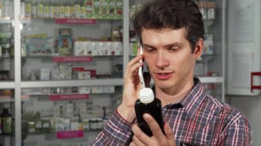 Eczanede alışveriş yaparken akıllı telefon kullanan genç adam